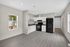 Modern kitchen with sleek black appliances, crisp white cabinetry, and elegant gray flooring, bathed in natural light from large windows.