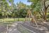 Inviting outdoor play area with wooden swing set surrounded by lush greenery and fenced garden space, perfect for family fun.