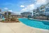 Luxurious apartment complex with inviting pool, stylish cabanas, and contemporary architecture under a bright blue sky.