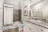 Elegant bathroom featuring a modern granite countertop, classic white cabinetry, and a sleek shower area with stylish tile accents.