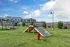 Gorgeous community playground featuring agility equipment against a backdrop of modern apartments and clear blue skies.