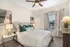 Cozy bedroom with elegant decor, featuring a plush bed with green and white pillows, modern artwork, and warm lighting.