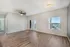 Bright, airy living space featuring sleek hardwood floors and stylish ceiling fan, with ample natural light from large windows and glass door leading to a serene outdoor view.