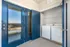 Modern apartment utility area with sleek blue French doors opening to a laundry nook equipped with a washer and dryer, featuring convenient shelving.