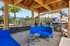 Inviting outdoor patio with bright blue seating under a wooden pergola, featuring modern grills and a scenic community backdrop.