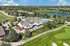 Luxurious aerial view of a clubhouse with a sparkling pool, surrounded by lush greenery and a serene lake, offering an inviting community atmosphere.