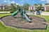 Charming residential community with vibrant playground surrounded by lush greenery and convenient parking.