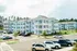 Charming residential complex featuring modern blue apartment buildings with spacious balconies, surrounded by lush green landscape and ample parking.