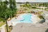 Luxurious apartment complex with a sparkling outdoor pool, comfortable lounge chairs, and lush green surroundings, perfect for relaxation and leisure.