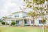 Charming suburban home with large windows, surrounded by lush greenery and palm trees, offering a welcoming and serene atmosphere.