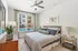 Modern, sunlit bedroom featuring elegant decor, plush bedding, and a charming plant beside the window with a view.