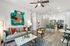 Chic open-concept living space featuring a stylish kitchen with modern appliances, cozy seating area with vibrant artwork, and elegant decor.