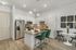 Modern kitchen with stainless steel appliances, granite countertops, and stylish lighting, featuring a cozy breakfast bar with green chairs.