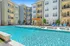 Modern apartment complex with inviting swimming pool, sun loungers, and a cozy wooden pergola, perfect for relaxation.