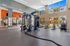 Modern fitness center featuring high ceilings, large windows with pool view, and a variety of exercise equipment.