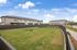 Inviting residential community with modern townhomes and expansive green space, perfect for relaxation and play under a clear blue sky.