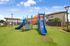 Vibrant outdoor playground with blue and orange slides set on lush green grass, perfect for family living in a welcoming neighborhood.