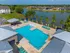 Luxurious lakeside apartment complex featuring a pristine swimming pool, spacious sundeck, and shaded pavilion with scenic waterfront views.