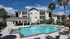 Elegant apartment complex with a sparkling outdoor pool, surrounded by lush palm trees and vibrant greenery, ideal for relaxation and leisure.
