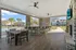 Charming outdoor lounge area featuring a spacious bar, stylish dining table, and scenic poolside view with palm trees.