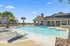 Luxurious outdoor pool area with sleek lounge chairs, surrounded by tropical palm trees and a charming clubhouse, perfect for relaxation and leisure.