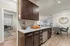 Elegant kitchen with stylish dark wood cabinets, granite countertops, and modern stainless steel appliances opening up to a cozy dining area and a spacious, light-filled home office.