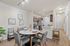 Contemporary apartment interior featuring a cozy dining area with modern chairs and a stylish round table, adjacent to a sleek kitchen with granite countertops and stainless steel appliances.