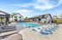 Modern outdoor pool area with stylish lounge chairs, luxurious sunbathing space, and contemporary clubhouse in the background.