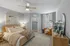 Serene bedroom with a cozy rattan bed, modern decor, and a plush upholstered chair by a large window, creating a tranquil oasis.