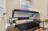 Bright and modern room featuring a sleek tanning bed under a window with elegant blinds, complemented by stylish hardwood floors.