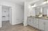 Modern bathroom with elegant granite countertop, spacious cabinetry, and a view into a walk-in closet. Bright lighting and stylish decor create a serene atmosphere.