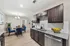 Modern kitchen and dining area with sleek dark wood cabinets, granite countertops, and vibrant blue chairs, complemented by a stylish chandelier and decor.