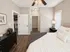 Inviting bedroom with cozy ambiance, featuring a comfortable bed, elegant lamp, sleek furniture, and warm wooden flooring.