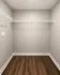 Spacious walk-in closet with elegant wooden flooring and ample shelving, perfect for organized living.
