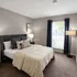 Inviting bedroom with plush bedding, elegant decor, and natural light streaming through large window.