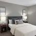 Cozy and elegant bedroom with a plush bed, stylish cushions, modern bedside lamps, and minimalist wall art.