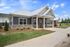 Charming modern home with stone accents and lush landscaping, nestled under a vibrant blue sky.