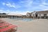 Inviting apartment community showcasing a sparkling pool with stylish red lounge chairs under a bright blue sky.
