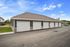 Modern apartment complex featuring a row of sleek garages with stylish stone and siding exterior, under a clear blue sky.