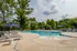Inviting outdoor pool area with elegant loungers, surrounded by lush greenery and shaded by stylish umbrellas, perfect for relaxing in sunny weather.