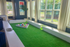Bright and inviting recreation room with expansive windows, vibrant turf flooring, and colorful billiard balls, offering a playful and refreshing ambiance.