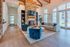 Inviting living room with luxurious blue velvet chairs, elegant stone fireplace, and abundant natural light.