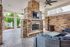 Charming outdoor living area with stone fireplace, inviting wicker seating, and lush greenery views.