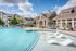 Luxurious apartment complex with a stunning outdoor pool, stylish loungers, and charming architecture under a clear blue sky.