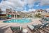 Luxurious apartment complex featuring a stunning resort-style swimming pool surrounded by elegant lounge chairs and lush landscaping.