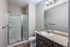 Modern bathroom with sleek shower, elegant brown vanity, and large mirror, perfect for a stylish home.