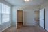Bright, carpeted bedroom with large window, spacious closet, and elegant ceiling fan; perfect for comfortable living.