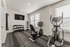 Modern home gym with exercise bike, elliptical, and free weights under natural light from large windows.