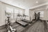 Modern in-house gym equipped with state-of-the-art treadmills, elliptical machine, and versatile strength training station with ample natural light.