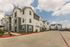Modern apartment complex exterior with stylish multi-story design, ample parking, and vibrant landscaping under a clear blue sky.
